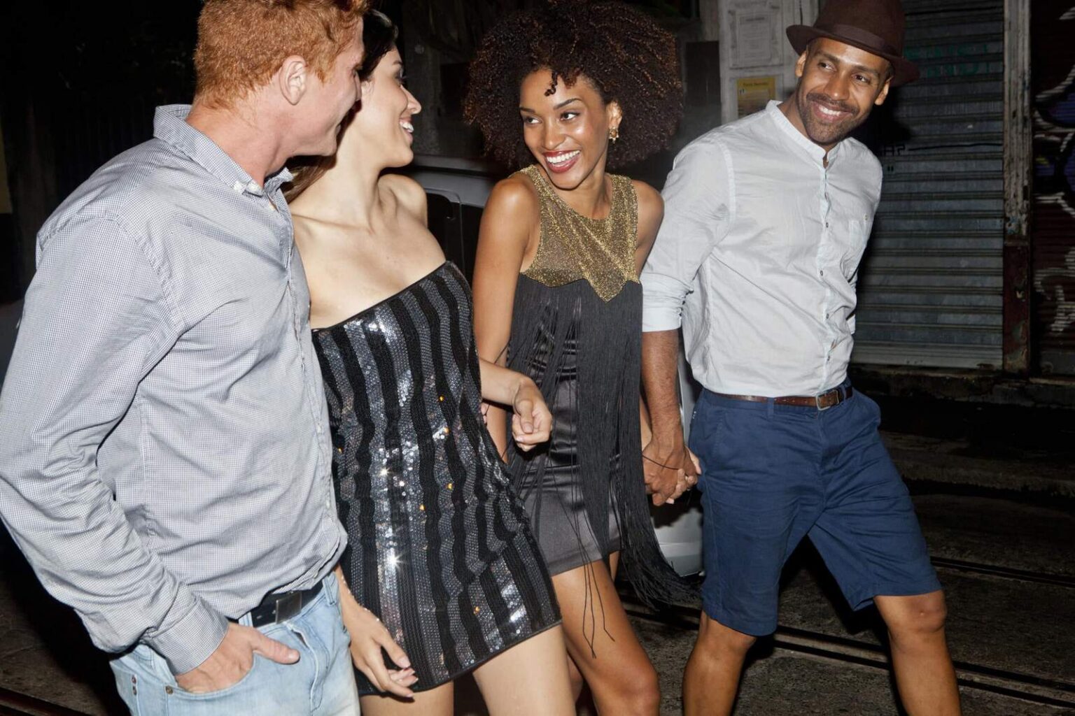 Four friends walking along a street on a night out